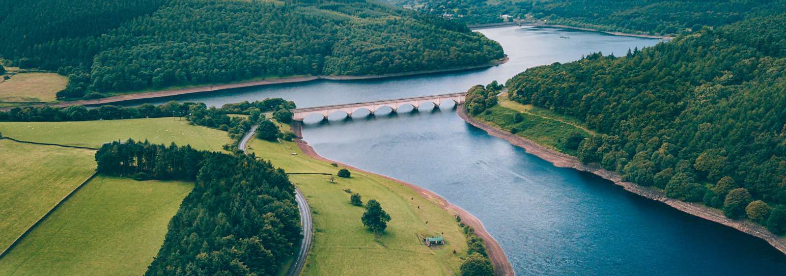 A bridge over a river surrounded by farm lands and forest